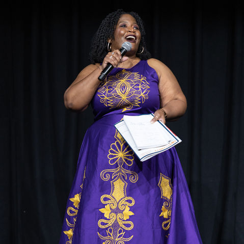 Beautiful Black woman in gown talking to crowd