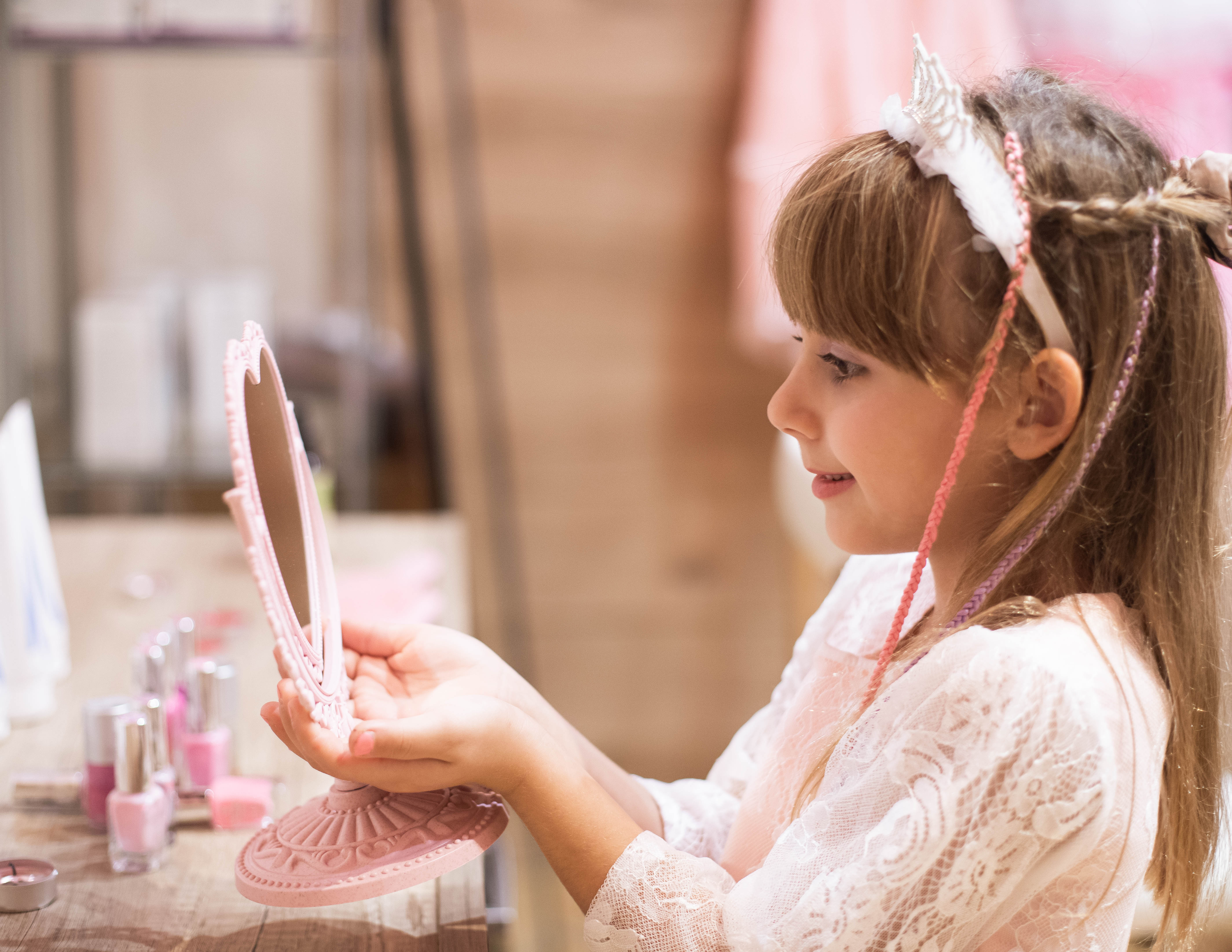 Bambina con corona si guarda in uno specchietto rosa — Princess Day