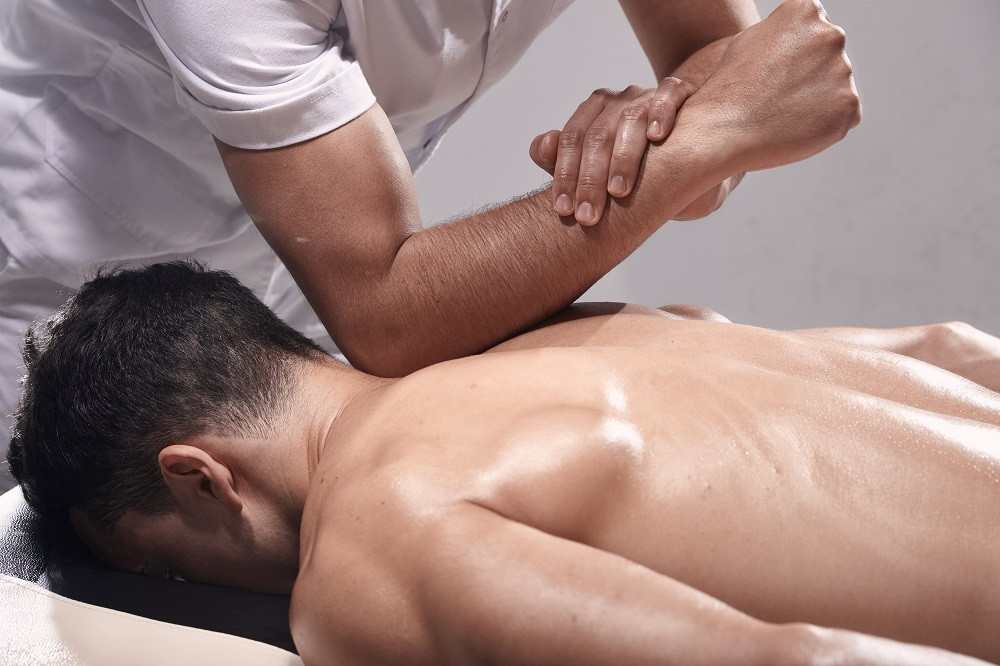Massage Therapist Massaging Man’s Back with Elbow