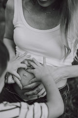 dłonie mamy i synka ułożone w serce na brzuszku ciążowym