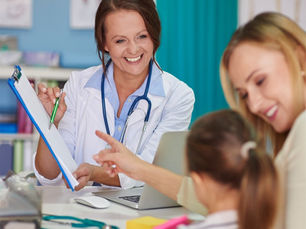 A lady doctor smiling at a women and a young girl