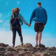 Couple holding hands on rocky shore