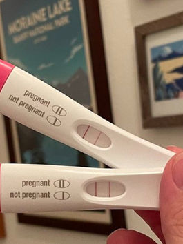 Hand holding two positive pregnancy tests