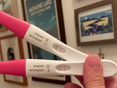 Hand holding two positive pregnancy tests