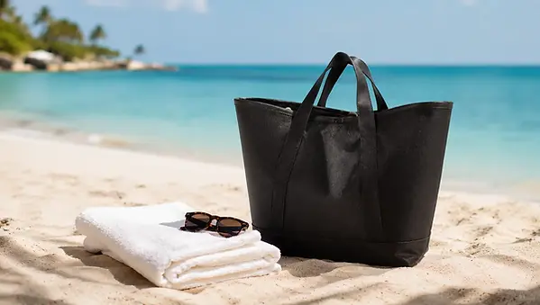 Reisenthel Shopper XL 35L strandtas in zwart op zandstrand met turquoise oceaan op achtergrond