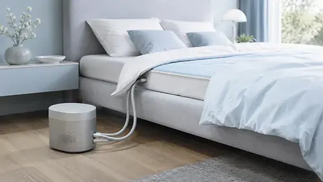 CLIMSOM Personal regelunit met dunne waterkoelmat op opgemaakt bed in moderne slaapkamer met zacht ochtendlicht