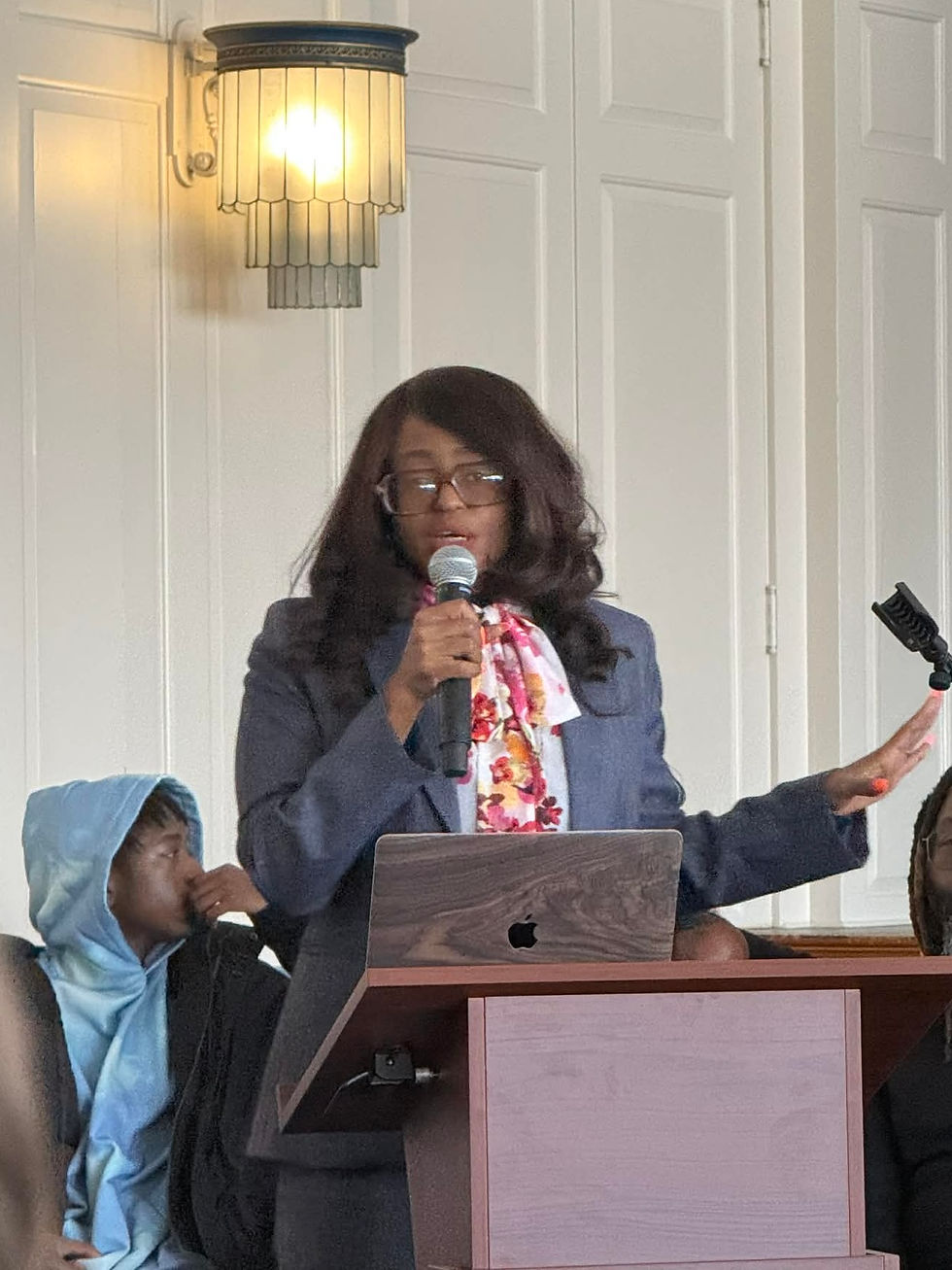 Adrienne Caulk gives speech at Penn Charter in a blue suit, floral top.