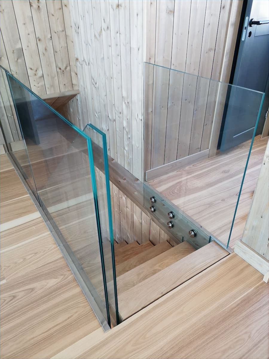 Glasräcken i härdat glas vid trätrappa med träpanel och trägolv i modern interiör
