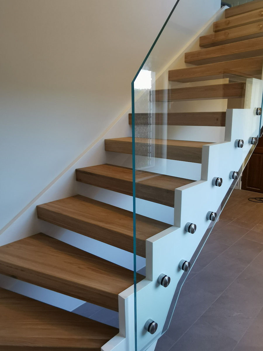 Glass railing along a wooden staircase with steel side structure in a modern interior