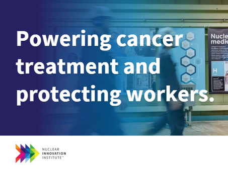 Workers in hard hats walk past posters about nuclear medicine. Text: "Powering cancer treatment and protecting workers."
