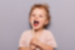 Portrait of laughing happy cheerful infant girl kid with curly blonde hair brushing her te
