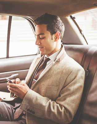 Businessman in a car on his phone browsing websites like Bird's Nest Marketing