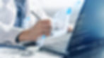 Doctor in a white coat writes on a document while using a laptop. Digital padlocks and papers hover, indicating data security. Blue and gray tones.