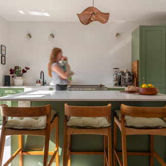 Beautiful green kitchen design with blurred person walking through the scene