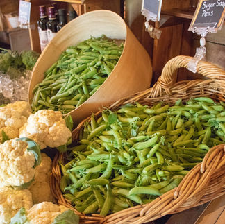Baskets of freshly picked sugar snap peas, shell peas, and cauliflower inside the farm market at Moulton Farm