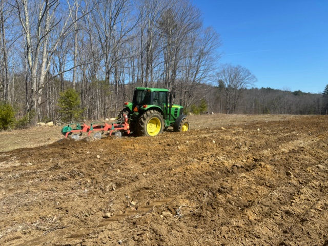 Green John Deere tractor plowing field at Moulton Farm on an early spring day