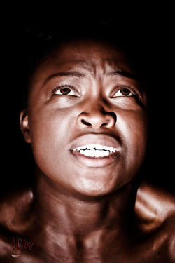 Tristesse - Photographie en clair-obscur par Dominique Dupray. Visage d'une femme à la peau noire su