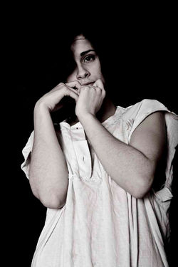 Repli - Photo en clair-obscur par Dominique Dupray d'un buste de femme. Sur un fond noir, elle fixe