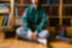 Lizzy Saxe sitting crosslegged in front of a bookshelf