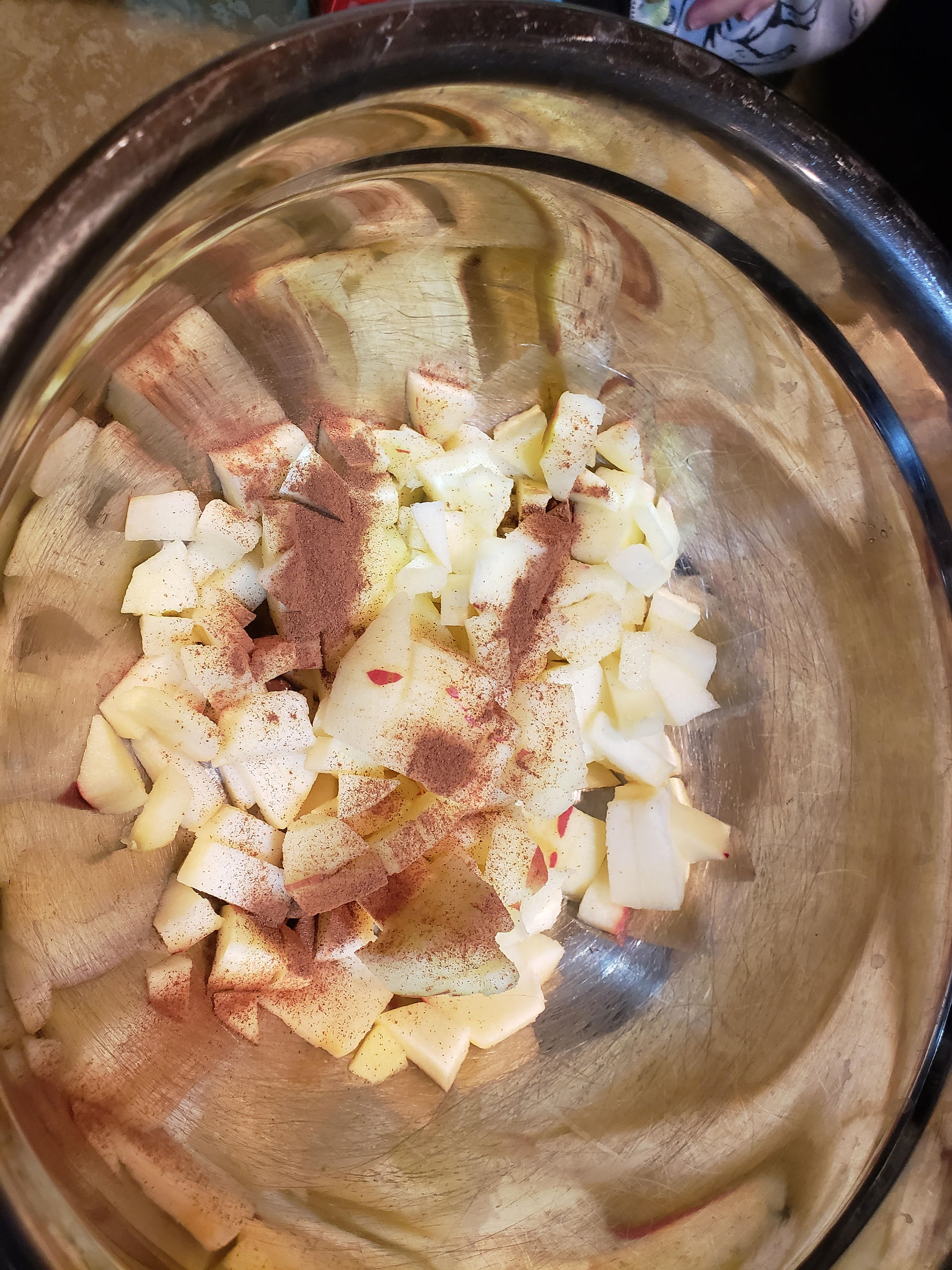 Small diced apples topped with cinnamon spice in a clear glass bowl.