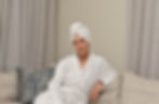 Beautiful woman in a white robe with a hair towel towel on her head, relaxing on a beige sofa