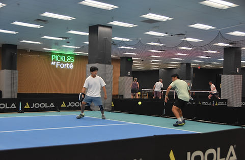 Men playing pickleball at pickles at forte.