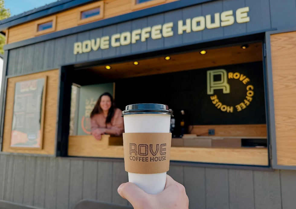 Holding a Rove Coffee infront of the custom business trailer.png