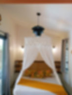 Chambre du lodge avec lit à baldaquin et linge jaune