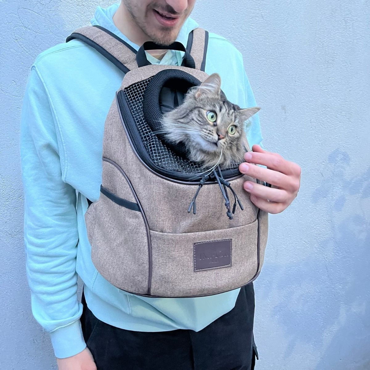 Homme porte un sac à dos pour chat avec un chat dedans. Flonimaux.
