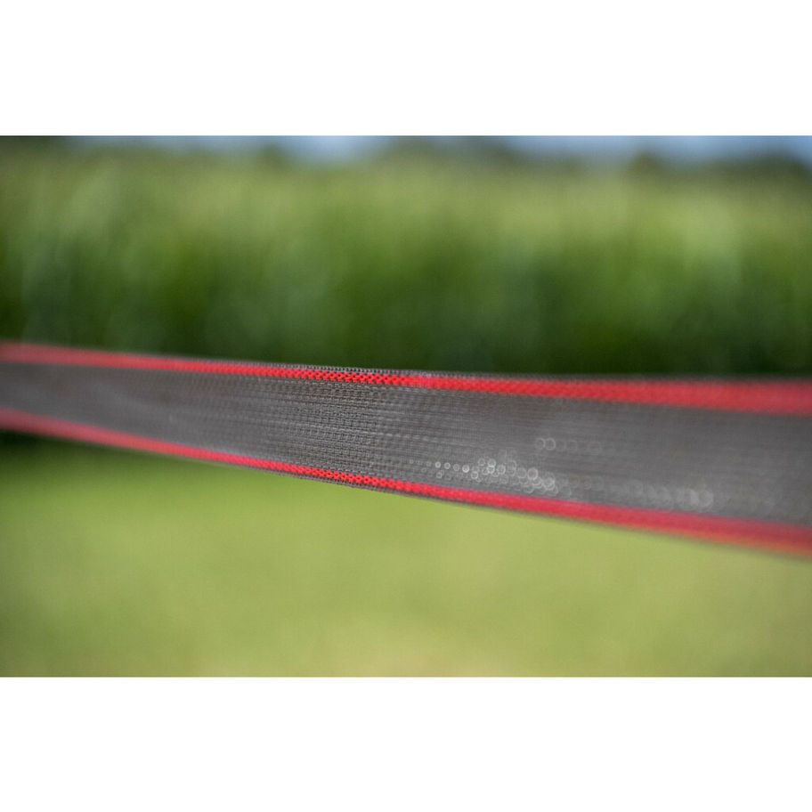 Ruban noir bordé de rouge en extérieur, arrière-plan flou vert.