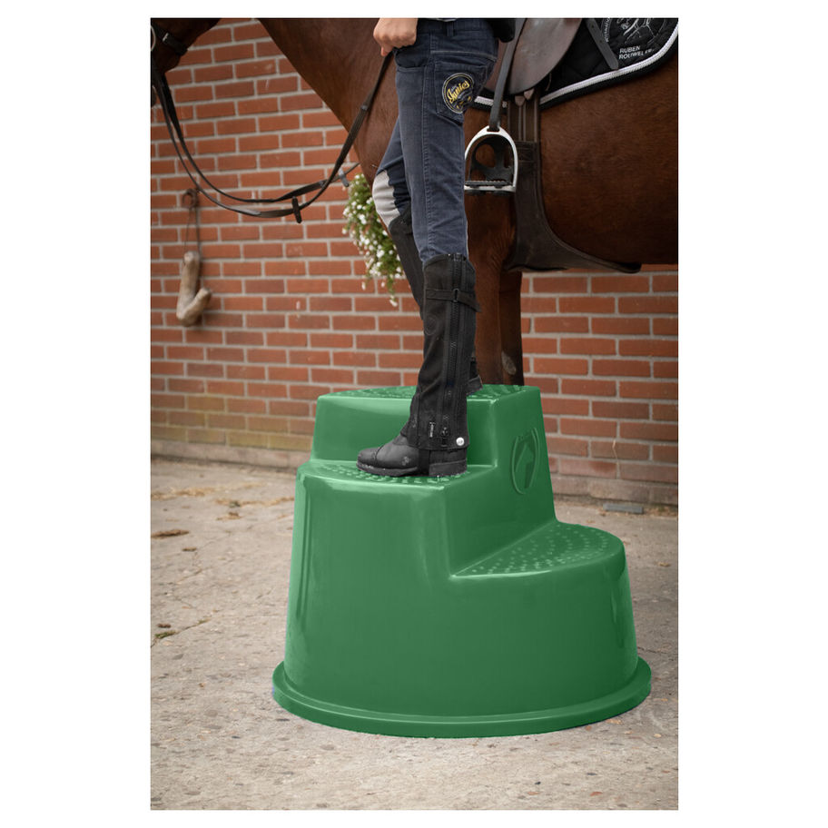 Cavalier monte sur un marchepied vert pour monter à cheval, à l'extérieur.
