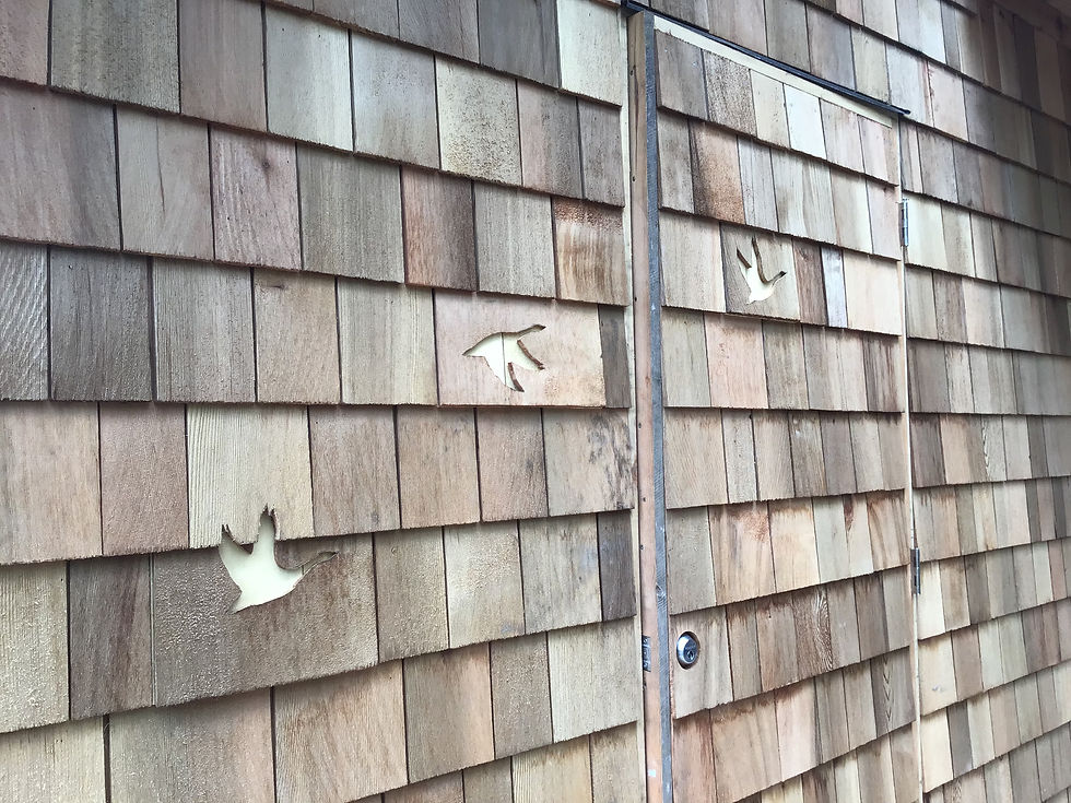 Birds cut into shingles on cabin wall