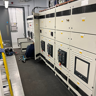 A technician works on an electrical panel in a control room