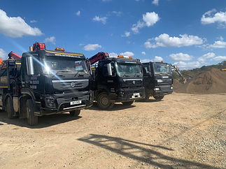 Fleet of three black Greenacre grab trucks parked on a dirt construction yard