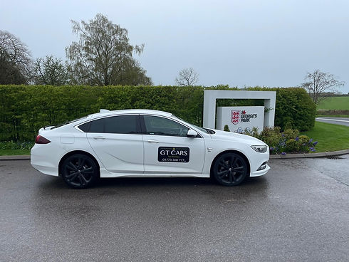 White GT Cars saloon vehicle parked outside a local community building