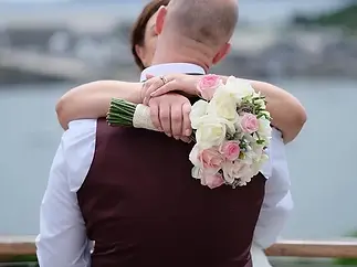 Close up of a groom’s hands holding a classic pink and white rose bridal bouquet
