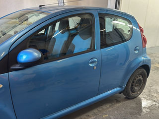 Completed car bodywork repair showing a fully restored and polished blue hatchback