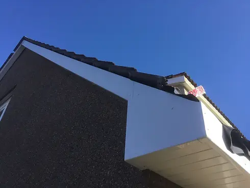 A house roof with mismatched tiles creating an optical illusion, under a clear blue sky