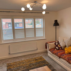 White cafe style window shutters installed in a brightly lit modern living room