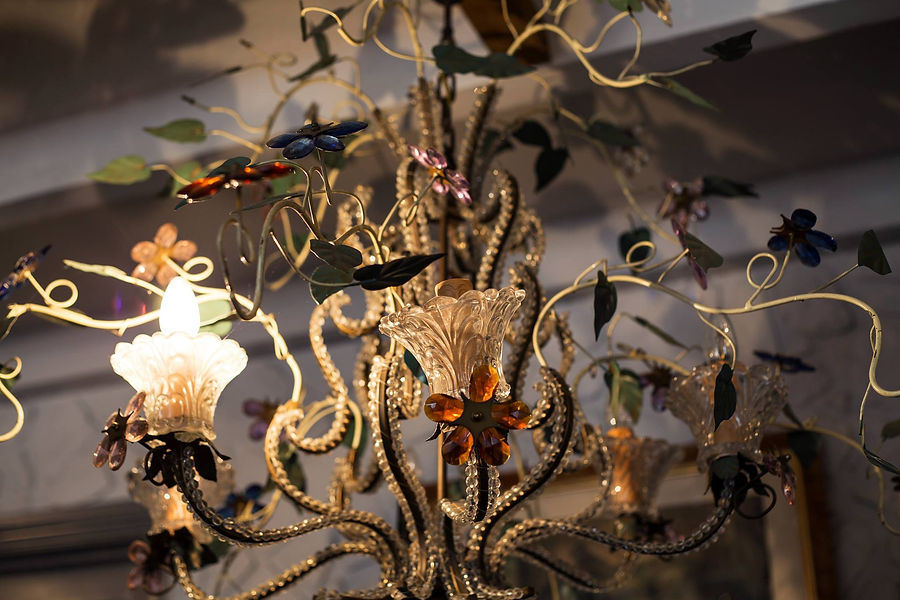 Close-up detail of an ornate vintage glass chandelier with delicate floral-shaped light fixtures