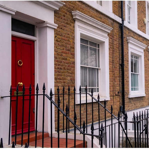 Traditional red front door next to white sash windows in London