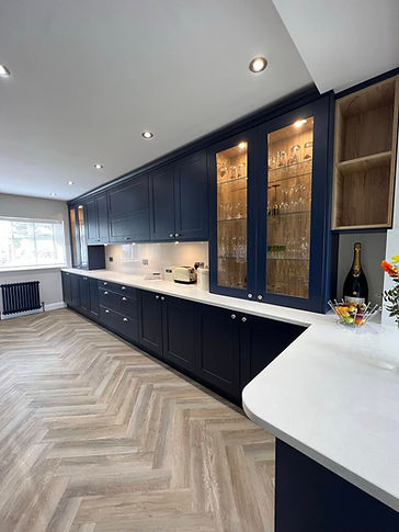 Long wall of bespoke deep navy blue kitchen cabinetry with illuminated glass front display cases