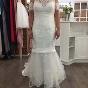Full length shot of a fitted mermaid style lace wedding dress in a showroom