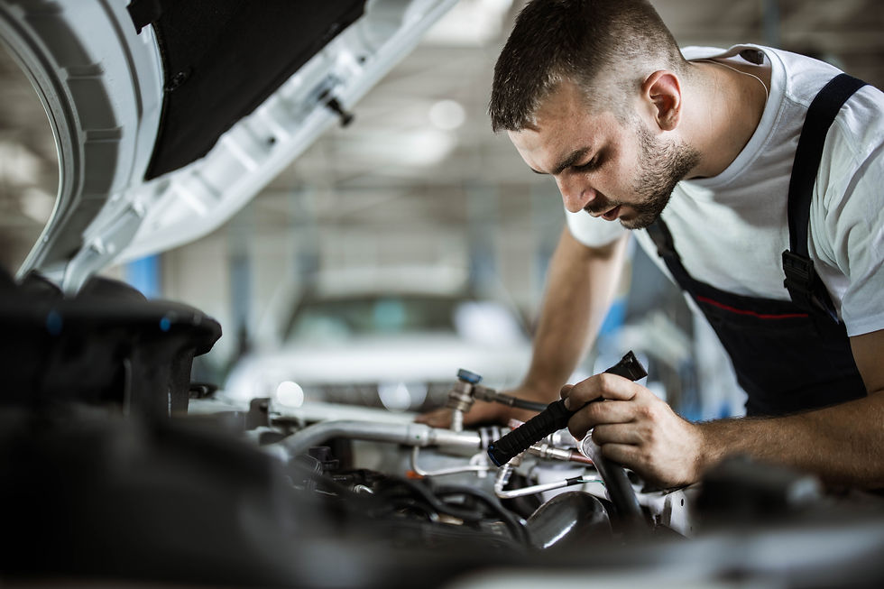 Focused local mechanic using a hand tool to repair components inside a car engine bay