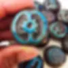 Close up of a hand holding a blue and black ceramic stone with an ancient symbol