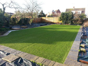 Landscaped garden featuring a perfectly level green lawn and timber border fencing