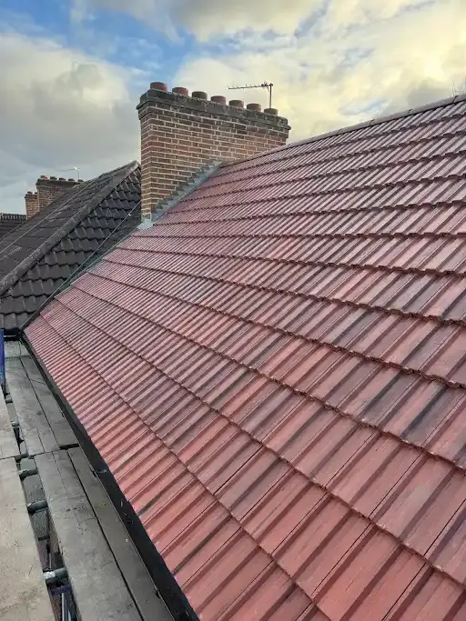 Newly laid red interlocking roof tiles and valley guttering