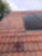 Red tiled roof with black solar panels installed