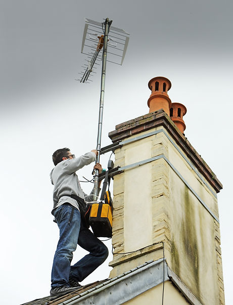 Technician mounting TV aerial on roof pole outdoors