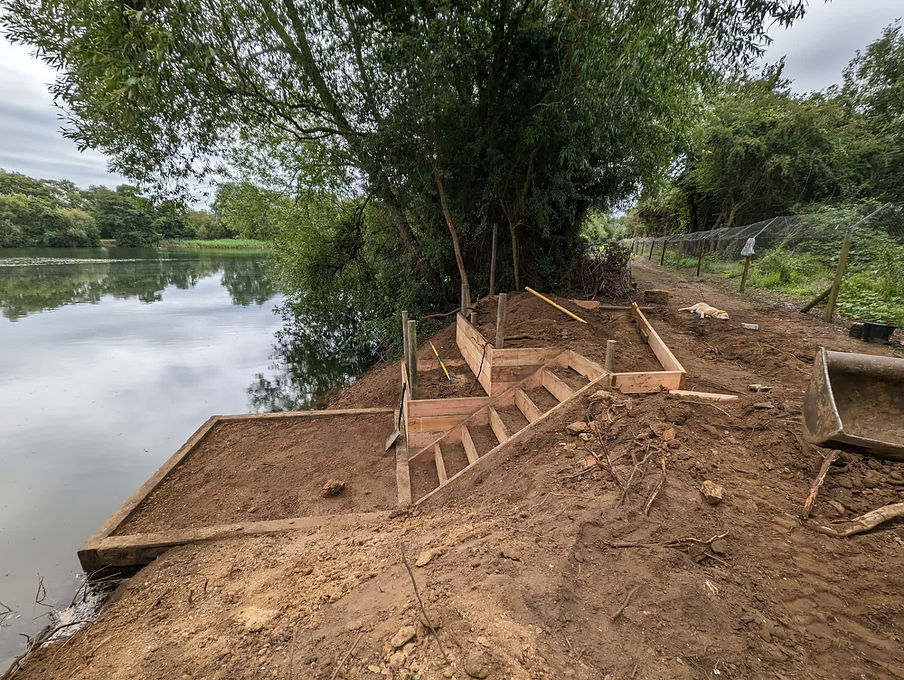 Newly constructed wooden steps and timber framework for a lakeside fishing platform